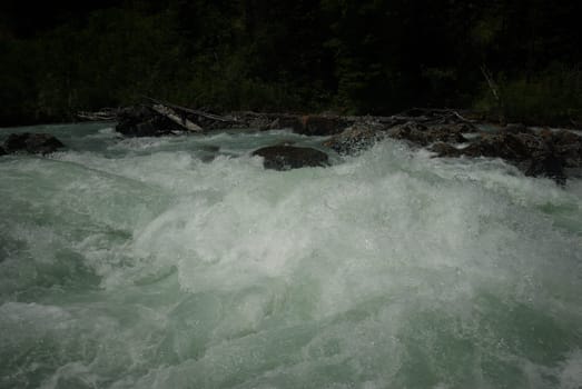 The mountain river in the mountains. Current through the gorge the river. Stones and rocky land near the river. Beautiful mountain landscape.