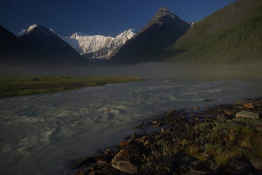 The mountain river in the mountains. Current through the gorge the river. Stones and rocky land near the river. Beautiful mountain landscape.