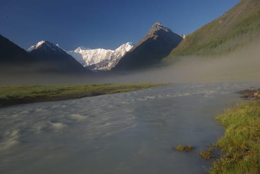 The mountain river in the mountains. Current through the gorge the river. Stones and rocky land near the river. Beautiful mountain landscape.