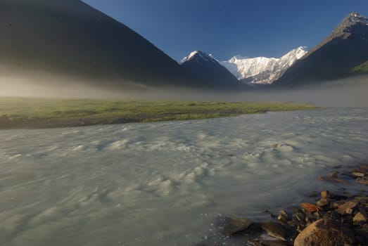 The mountain river in the mountains. Current through the gorge the river. Stones and rocky land near the river. Beautiful mountain landscape.