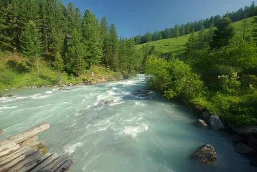 The mountain river in the mountains. Current through the gorge the river. Stones and rocky land near the river. Beautiful mountain landscape.