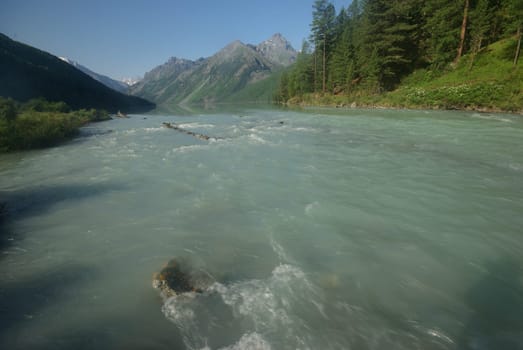 The mountain river in the mountains. Current through the gorge the river. Stones and rocky land near the river. Beautiful mountain landscape.