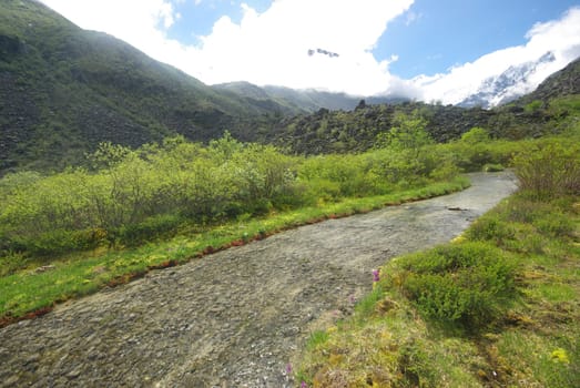 The mountain river in the mountains. Current through the gorge the river. Stones and rocky land near the river. Beautiful mountain landscape.