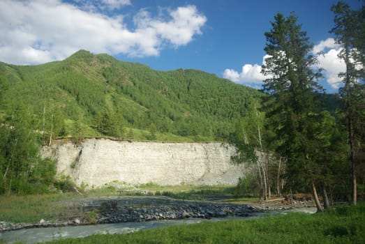 The mountain river in the mountains. Current through the gorge the river. Stones and rocky land near the river. Beautiful mountain landscape.