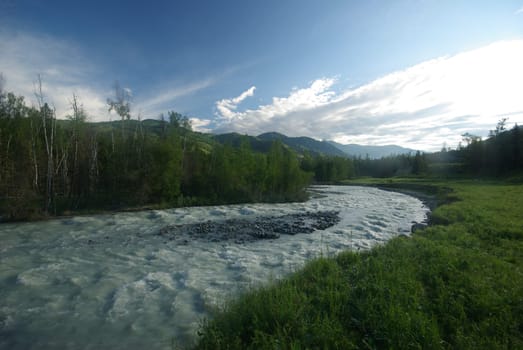 The mountain river in the mountains. Current through the gorge the river. Stones and rocky land near the river. Beautiful mountain landscape.