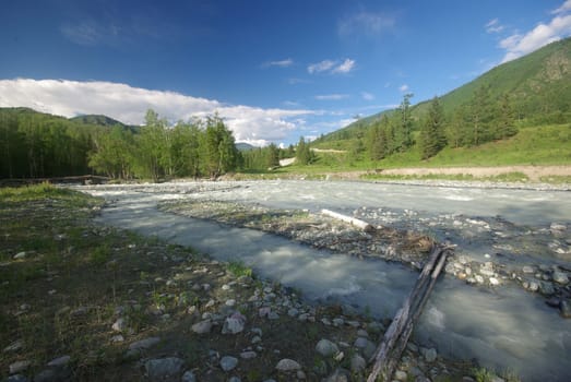 The mountain river in the mountains. Current through the gorge the river. Stones and rocky land near the river. Beautiful mountain landscape.