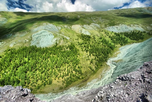 The mountain river in the mountains. Current through the gorge the river. Stones and rocky land near the river. Beautiful mountain landscape.