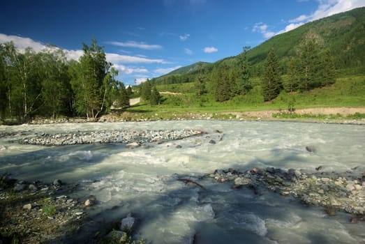 The mountain river in the mountains. Current through the gorge the river. Stones and rocky land near the river. Beautiful mountain landscape.