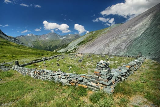 The mountain river in the mountains. Current through the gorge the river. Stones and rocky land near the river. Beautiful mountain landscape.