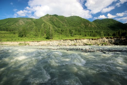The mountain river in the mountains. Current through the gorge the river. Stones and rocky land near the river. Beautiful mountain landscape.
