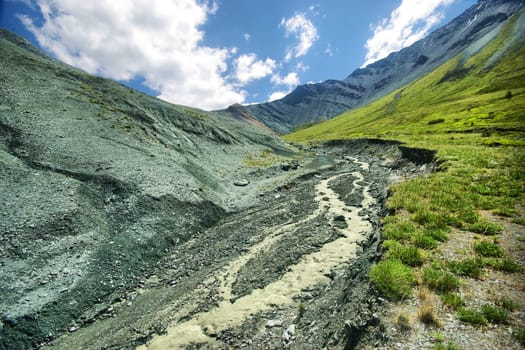 The mountain river in the mountains. Current through the gorge the river. Stones and rocky land near the river. Beautiful mountain landscape.