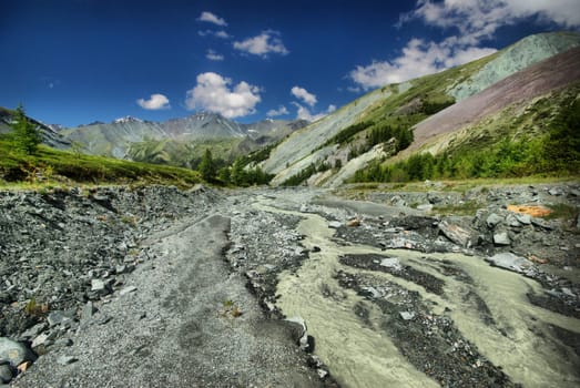 The mountain river in the mountains. Current through the gorge the river. Stones and rocky land near the river. Beautiful mountain landscape.