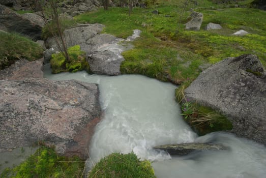 The mountain river in the mountains. Current through the gorge the river. Stones and rocky land near the river. Beautiful mountain landscape.