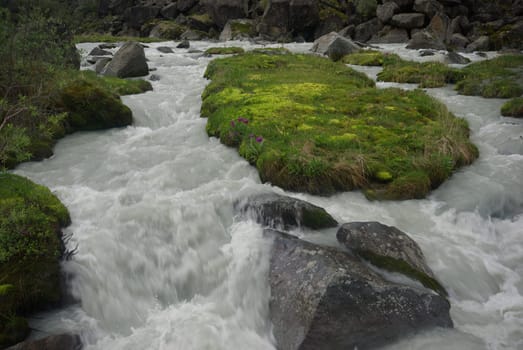 The mountain river in the mountains. Current through the gorge the river. Stones and rocky land near the river. Beautiful mountain landscape.