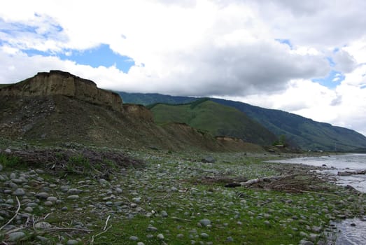 The mountain river in the mountains. Current through the gorge the river. Stones and rocky land near the river. Beautiful mountain landscape.