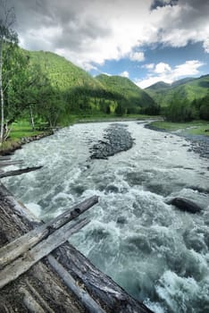 The mountain river in the mountains. Current through the gorge the river. Stones and rocky land near the river. Beautiful mountain landscape.