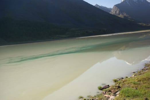 The mountain river in the mountains. Current through the gorge the river. Stones and rocky land near the river. Beautiful mountain landscape.