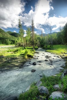 The mountain river in the mountains. Current through the gorge the river. Stones and rocky land near the river. Beautiful mountain landscape.