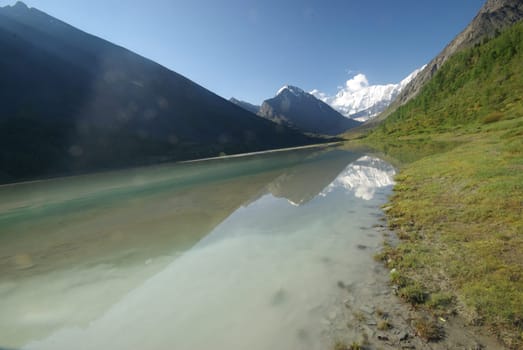 The mountain river in the mountains. Current through the gorge the river. Stones and rocky land near the river. Beautiful mountain landscape.