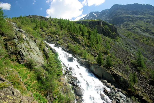 The mountain river in the mountains. Current through the gorge the river. Stones and rocky land near the river. Beautiful mountain landscape.