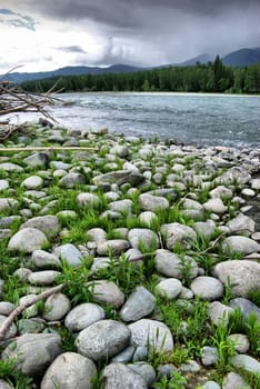 The mountain river in the mountains. Current through the gorge the river. Stones and rocky land near the river. Beautiful mountain landscape.