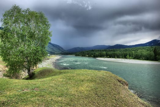 The mountain river in the mountains. Current through the gorge the river. Stones and rocky land near the river. Beautiful mountain landscape.