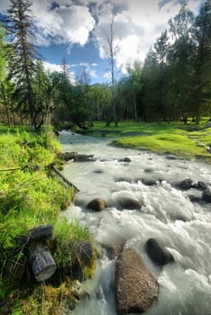 The mountain river in the mountains. Current through the gorge the river. Stones and rocky land near the river. Beautiful mountain landscape.