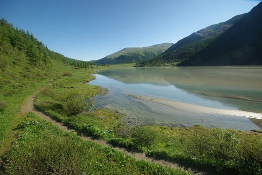 The mountain river in the mountains. Current through the gorge the river. Stones and rocky land near the river. Beautiful mountain landscape.