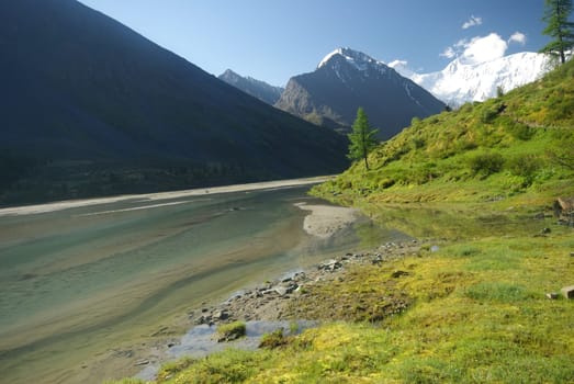 The mountain river in the mountains. Current through the gorge the river. Stones and rocky land near the river. Beautiful mountain landscape.