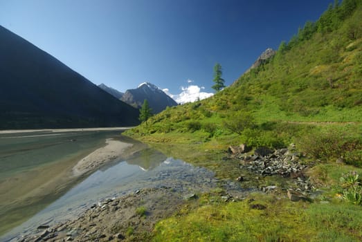 The mountain river in the mountains. Current through the gorge the river. Stones and rocky land near the river. Beautiful mountain landscape.