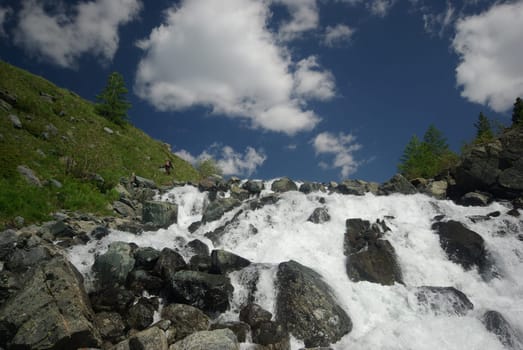 The mountain river in the mountains. Current through the gorge the river. Stones and rocky land near the river. Beautiful mountain landscape.