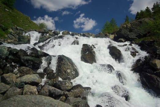 The mountain river in the mountains. Current through the gorge the river. Stones and rocky land near the river. Beautiful mountain landscape.