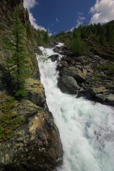 The mountain river in the mountains. Current through the gorge the river. Stones and rocky land near the river. Beautiful mountain landscape.