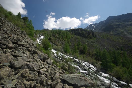 The mountain river in the mountains. Current through the gorge the river. Stones and rocky land near the river. Beautiful mountain landscape.