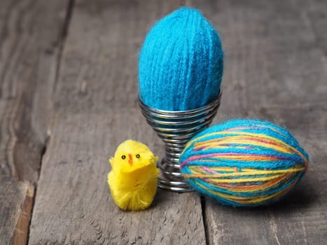 Two Easter eggs covered with wool yarn on a rutsic wooden table
