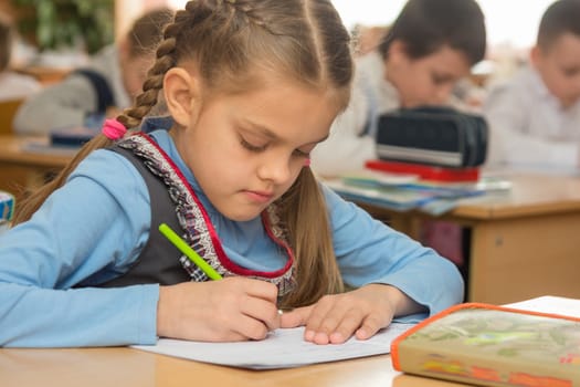 First grader in class writing in notebook