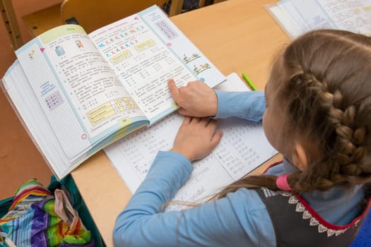 Anapa, Russia - February 28, 2017: First grader reads the task in the textbook running his finger under the text