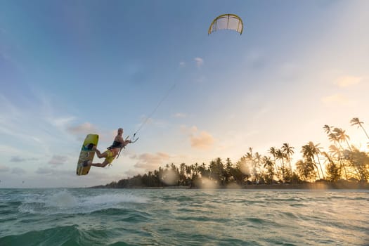 Kiteboarding. Fun in the ocean. Extreme Sport Kitesurfing. Kitesurfer jumping high in the air during dusk moonlight lit session.