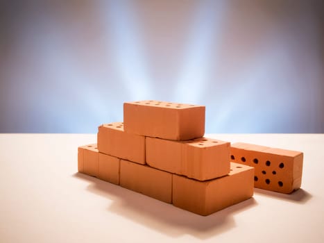 Stacked model bricks on a white background with a star-shaped illuminated background.