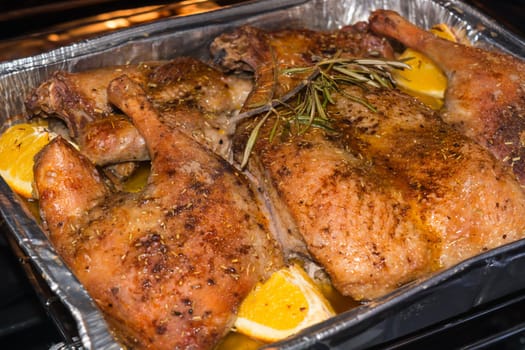 Crispy roast duck in an aluminum bowl in the oven.
