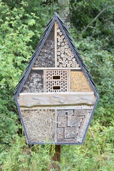 A small insect hotel with a pointed roof.