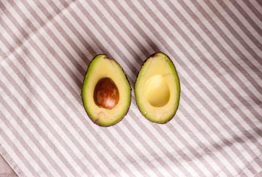 closeup cut fresh avocado on stripped tablecloth