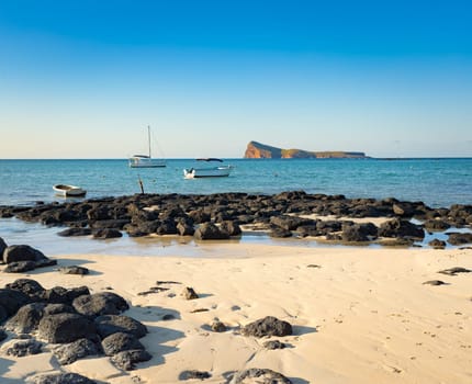 Boats in a sea at day time. Flat island on a background. Mauritius
