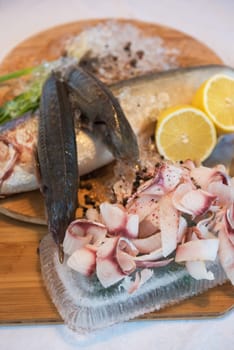 Sliced frozen raw fish from whitefish species - white salmon, whitefish, decorated with whole fishes, ice, lemon and greens. Siberian cuisine