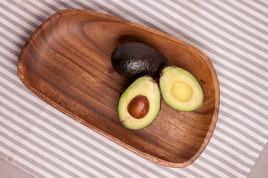 closeup cut avocado on wooden plate at table