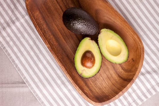 closeup cut avocado on wooden plate at table