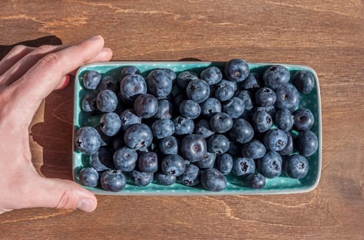 fresh big delicious blueberries in rectangular green plate wooden background