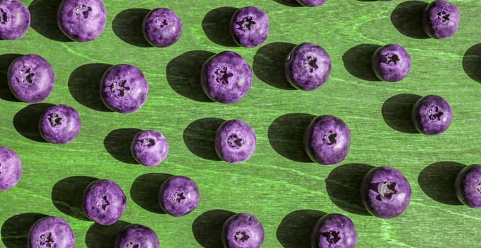 big violet toned blueberries wooden green background bright shadows