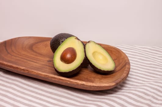 closeup cut avocado on wooden plate at table