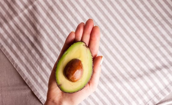 closeup cut avocado in women hand over table